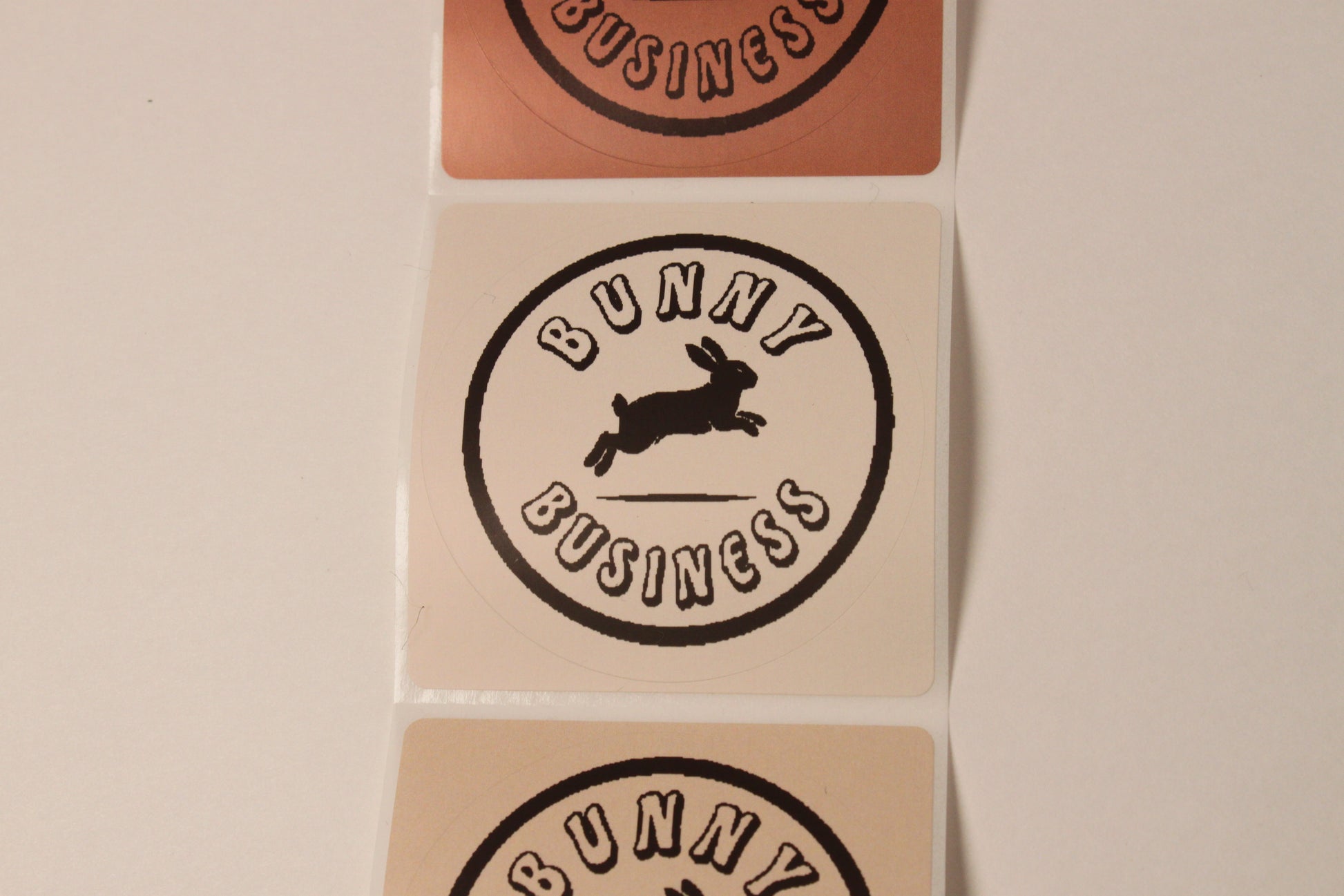 Three 'Bunny Business' stickers on a beige background
