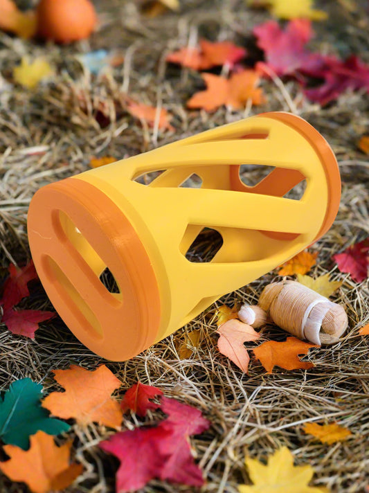 Yellow and orange hay roller rabbit toy laying on hay and autumn leaves