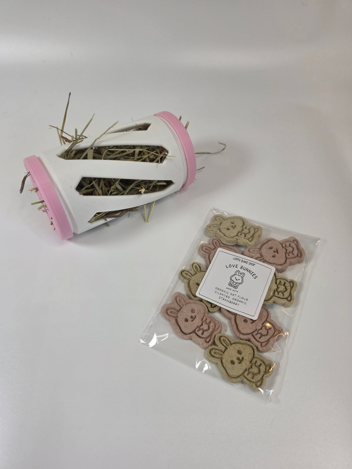 a hay roller and a bag of rabbit treats against a white background
